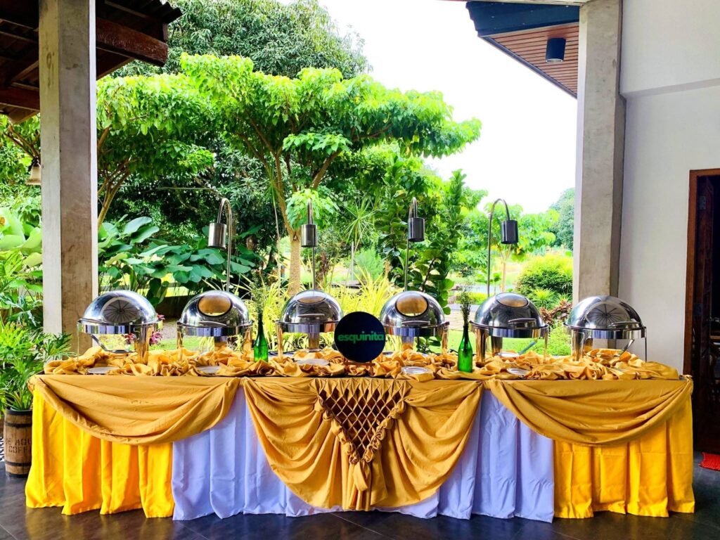 Cafe Esquinita catering buffet table with gold drapes and chafing dishes in Malaybalay City, Bukidnon