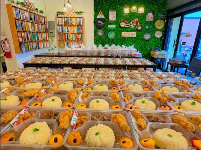 Rows of Cafe Esquinita packed lunches with rice, fried chicken and muffins ready for a group order in Malaybalay City