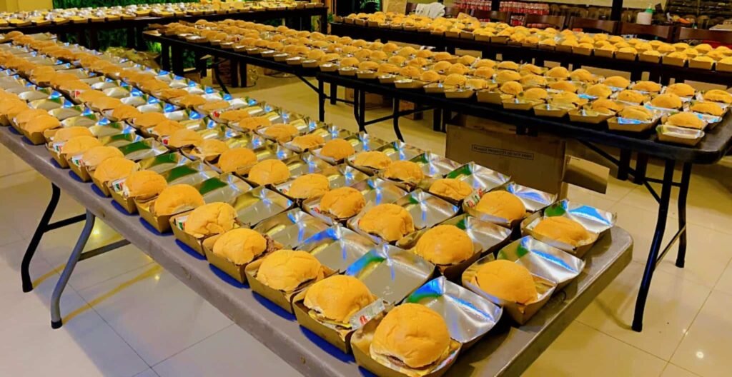 Tables of Cafe Esquinita snack packs with burgers in boxes ready for a large group order in Malaybalay City